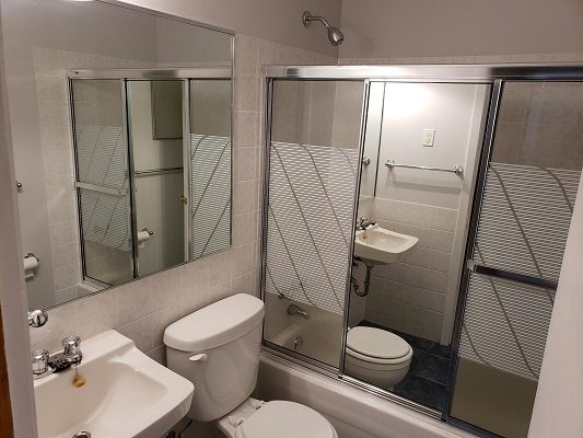 A bathroom with a toilet, sink and shower.