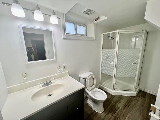 A bathroom with a toilet, sink and shower.