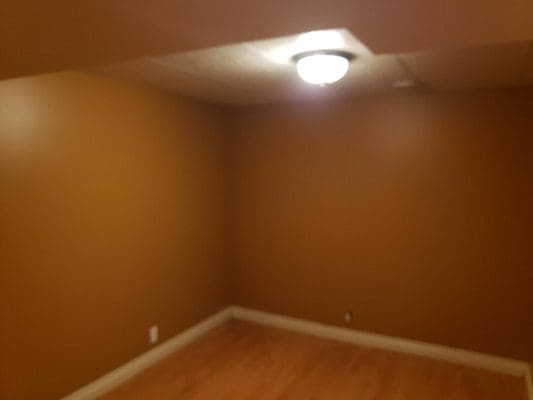 An empty room with brown walls and hardwood floors.