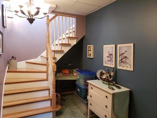 A room with a staircase and a dresser.