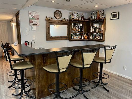 A home bar with four stools and a bottle of liquor.