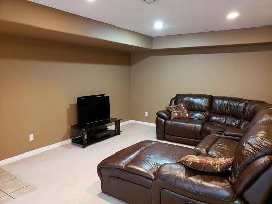 A living room with brown leather furniture and a tv.