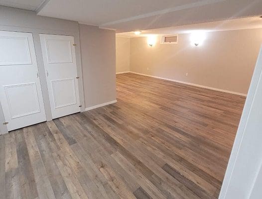 An empty room with wood floors and white walls.