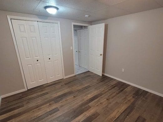 Empty room with hardwood floors and closets.