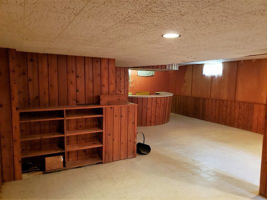 An empty basement with wood paneling and shelves.