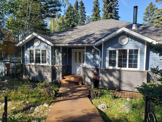 A house in the woods with a wooden walkway.