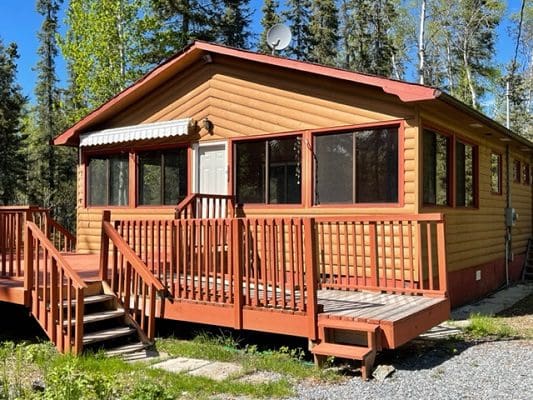 A cabin in a wooded area with a deck.