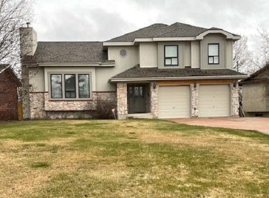 A home with a garage and grass in front of it.