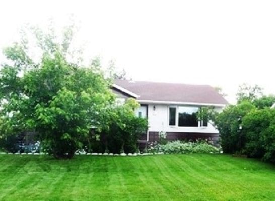 A house with a lawn and trees in front of it.