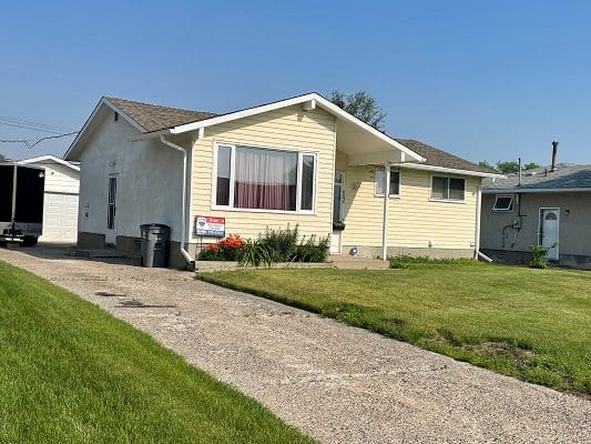 A house with a lawn and a garage in front of it.