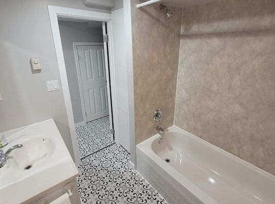 A bathroom with tile floors and a bathtub.