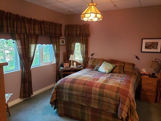 A bedroom with a plaid comforter and a window.