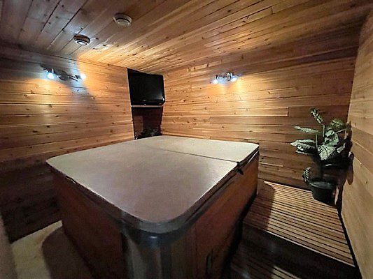 A hot tub in a room with wooden walls.