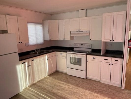 An empty kitchen with white cabinets and a stove.