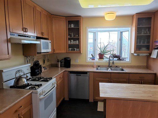 A kitchen with a stove, sink, and a window.