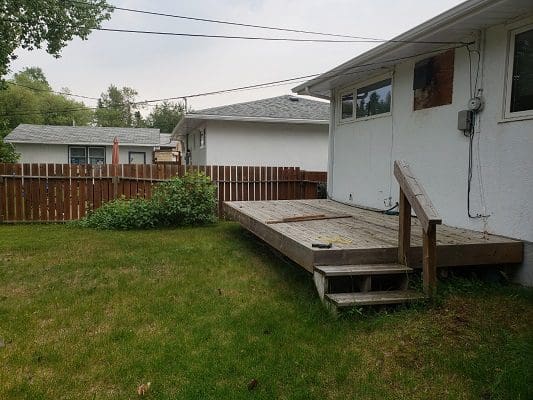 A backyard with a wooden deck and a wooden fence.