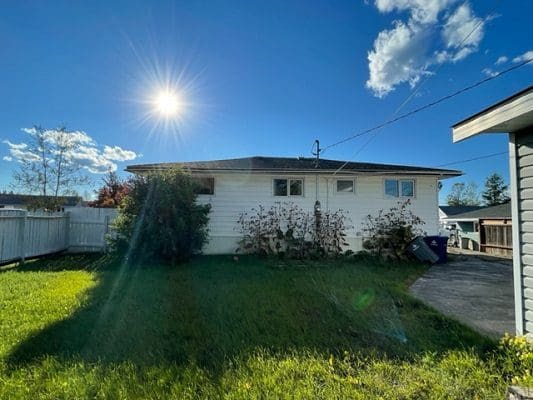 The backyard of a house with a sun shining on it.