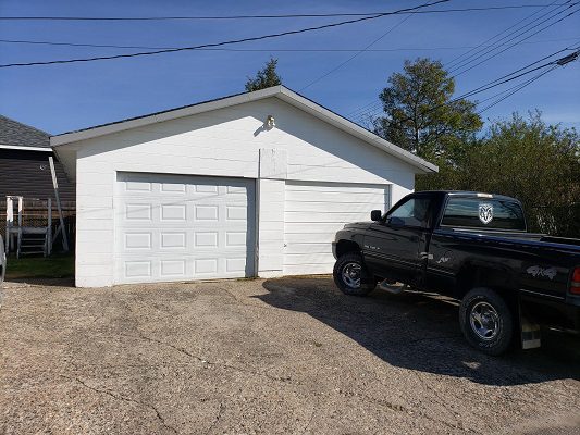 A black truck is parked in front of a garage.