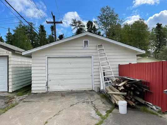 A garage with a red door and a ladder.