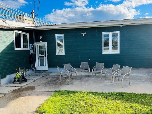A green house with a patio and chairs.