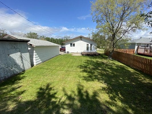 A backyard with a grassy area and a fence.