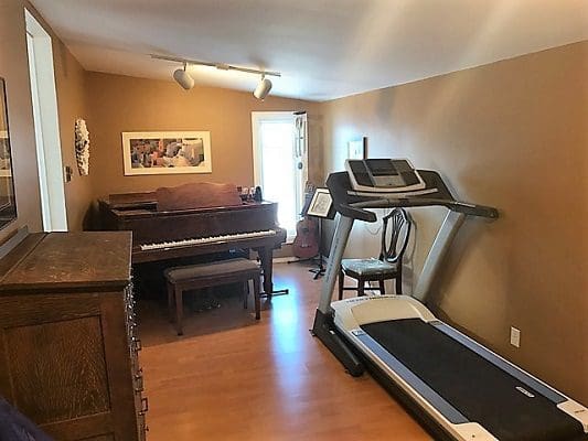 A room with a piano and a treadmill.