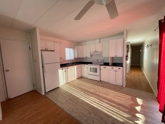 An empty kitchen with white cabinets and a ceiling fan.