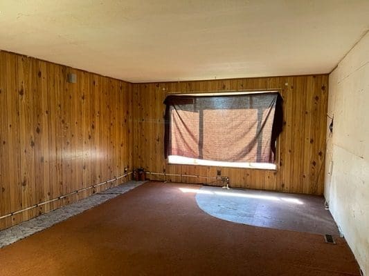 An empty room with wood paneling and a window.