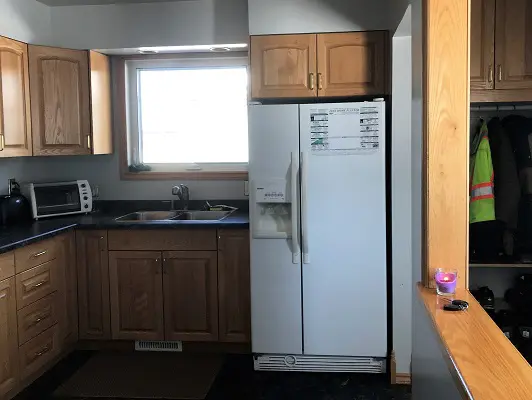 A kitchen with wood cabinets and a refrigerator.