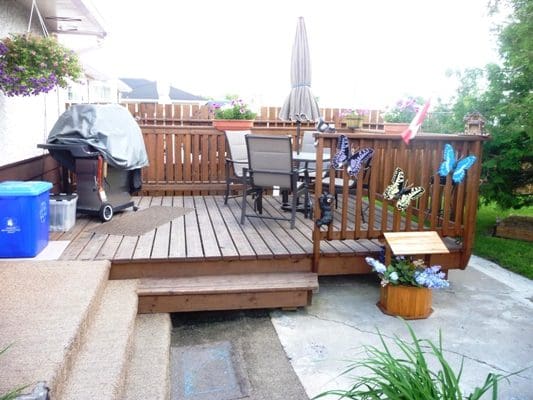 A backyard with a wooden deck and patio furniture.
