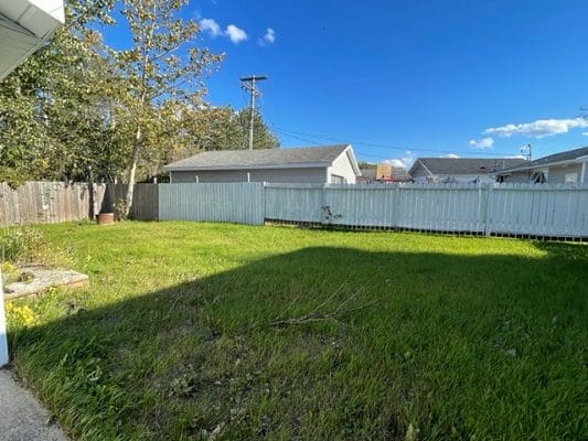 A backyard with grass and a fence.