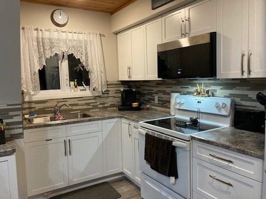 A kitchen with white cabinets and a microwave.
