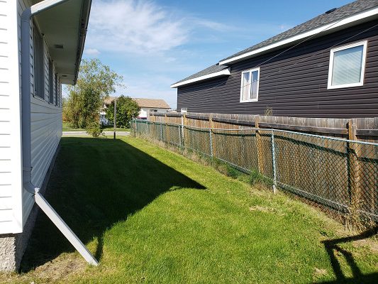 A backyard with a fence and a grassy area.