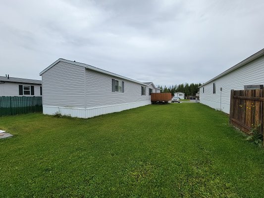 Two mobile homes in a grassy area.