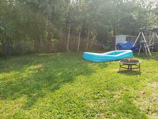 A backyard with an inflatable pool and a fire pit.