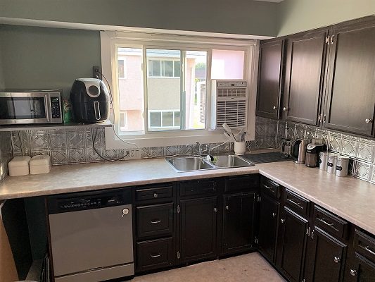 A kitchen with brown cabinets and a microwave.