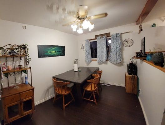 A kitchen with a table and chairs and a ceiling fan.