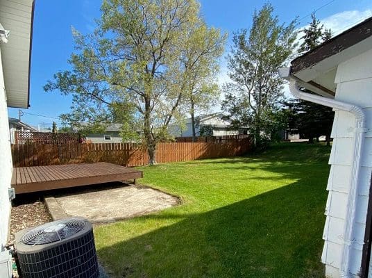 A backyard with an air conditioner and a wooden deck.