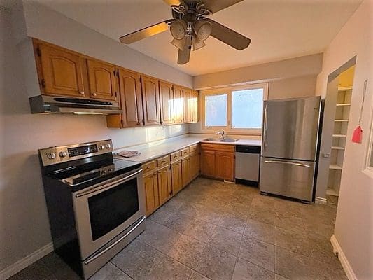 A kitchen with stainless steel appliances and a ceiling fan.