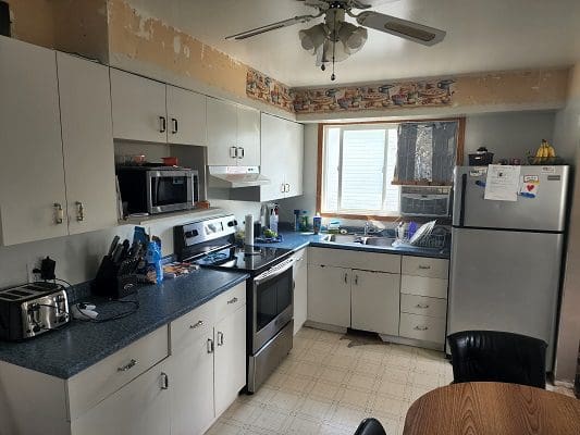 A kitchen with white cabinets and a ceiling fan.