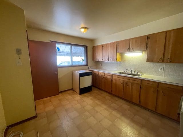 An empty kitchen with wooden cabinets and a microwave.