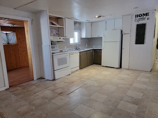 An empty kitchen with a stove and refrigerator.
