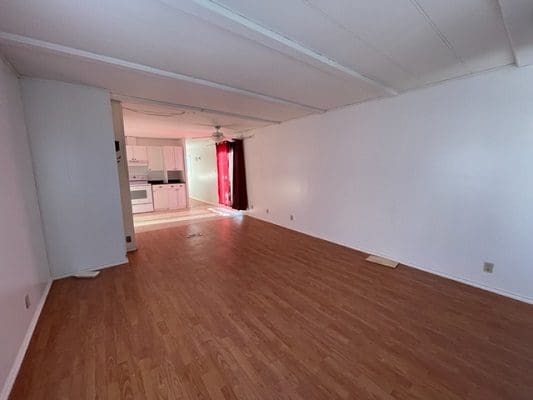 Empty living room with hardwood floors and white walls.