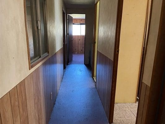 A hallway with wood paneling and a window.