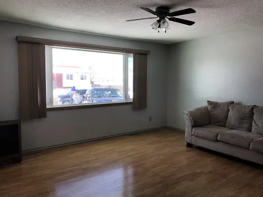 A living room with hardwood floors and a ceiling fan.