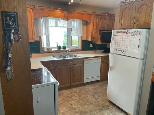 A kitchen with white cabinets and a refrigerator.