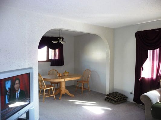 A living room with a tv and a dining table.