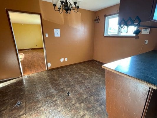 An empty kitchen with brown walls and a wooden floor.