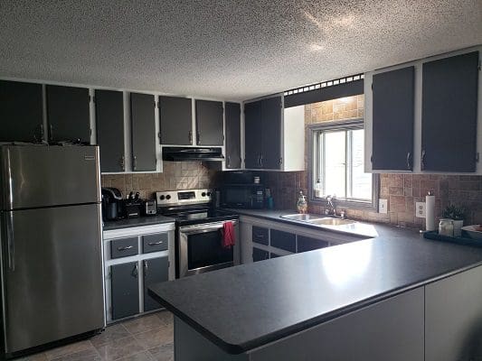 A kitchen with gray cabinets and stainless steel appliances.