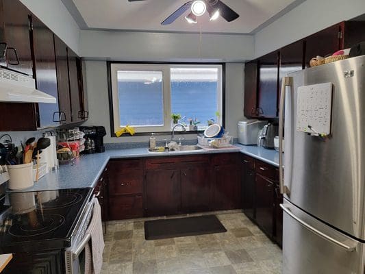 A kitchen with stainless steel appliances and a ceiling fan.